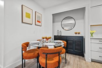 A dining room with a round table and orange chairs.
